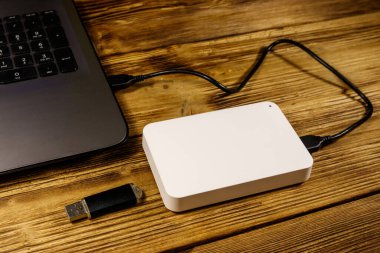 Harici HDD, tahta bir masadaki dizüstü bilgisayara ve USB flash diske bağlı. Veri depolama kavramı