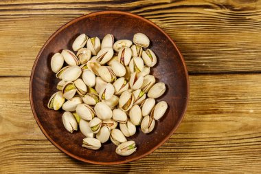 Ahşap bir masada seramik tabakta fıstıklar. Üst görünüm