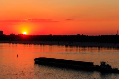 Römorkör, gün batımında Dinyeper nehrinde ağır, uzun bir mavnayı itiyor.