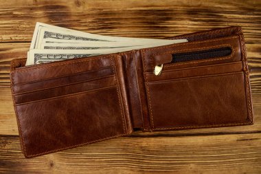 Ahşap masanın üzerinde Amerikan doları olan açık cüzdan. Üstte görüntü