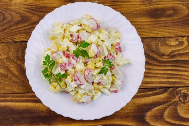 Yengeç saplı salata, tatlı mısır, Çin lahanası, yumurta ve mayonez ahşap masada.