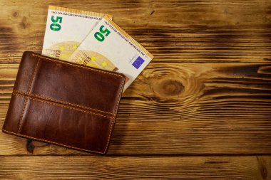 Ahşap arka planda cüzdan ve elli avroluk banknotlar
