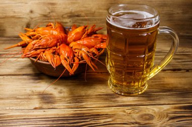 Haşlanmış kerevit ve bir kupa bira ahşap masada.
