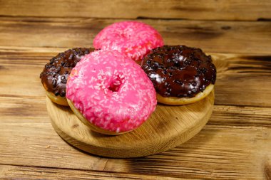 Tahta bir masada lezzetli pembe ve çikolatalı çörekler.