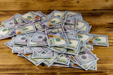 Tahta bir masanın üzerine yığınla Amerikan 100 dolarlık banknot.
