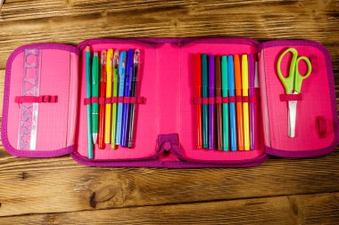 Kalem, kalem, keçeli kalem, makas ve cetvel içeren tahta masa. Üst görünüm