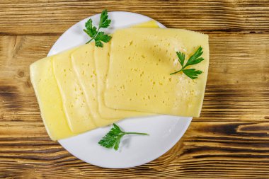 Tahta masadaki bir tabakta peynir dilimleri. Üst görünüm