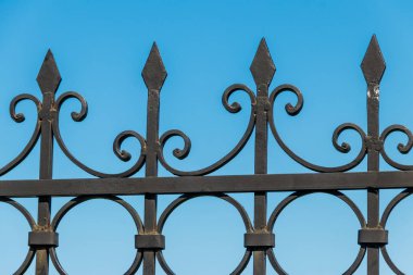 Şehir parkında siyah işlemeli demir çitler.