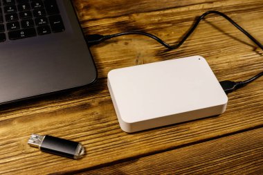 Harici HDD, tahta bir masadaki dizüstü bilgisayara ve USB flash diske bağlı. Veri depolama kavramı