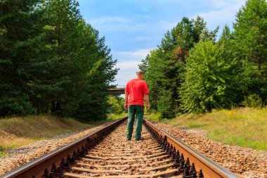 Yalnız adam tren yolunda yürüyor.