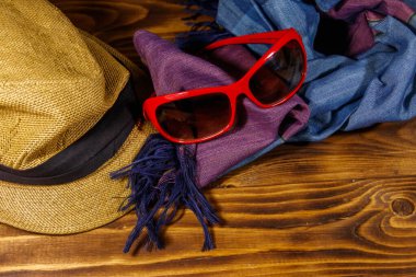 Kırmızı güneş gözlüğü, hasır şapka ve tahta arka planda yaz atkısı. Kadın moda aksesuarları. Yaz tatili ve seyahat konsepti