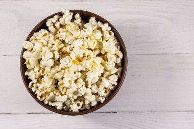 Beyaz ahşap masada patlamış mısırlı bir kase. Üst görünüm