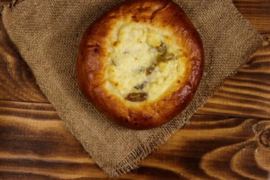 Ahşap masada süzme peynir ve kuru üzümlü (cheesecake) tatlı yuvarlak çörek. Üst görünüm