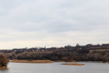Baharın erken saatlerinde bulutlu bir günde nehir ve köy manzarası
