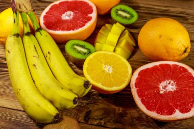Ahşap masa üzerinde tropikal meyve çeşitleri. Muz, mango, portakal, greyfurt ve kivi ile natürmort
