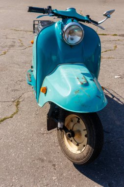 Şehrin caddesinde park etmiş mavi scooter.