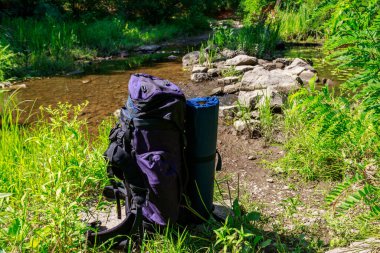 Yaz aylarında bir nehir yakınında turist sırt çantası. Zam konsepti