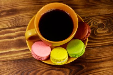 Bir fincan kahve ile lezzetli renkli macarons ahşap masa üzerinde. Üstten görünüm