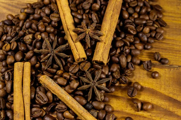 Roasted coffee beans, cinnamon sticks and star anise on rustic wooden background