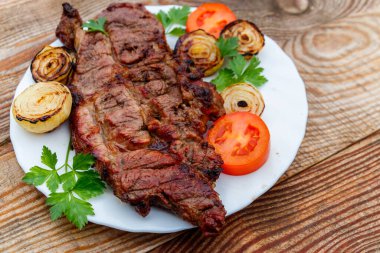 Izgara domuz etli soğan, domates ve maydanoz ahşap masa üzerinde beyaz plaka