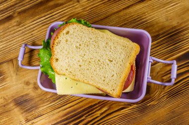 Tahta bir masanın üzerinde sandviçlerle beslenme çantası. Üst görünüm