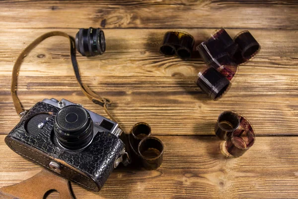 Retro photo camera with photo film and lens on wooden table