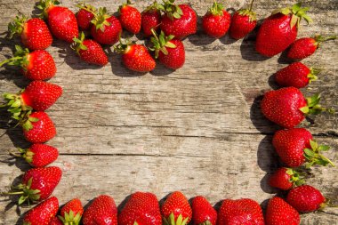 Taze kırmızı çilek çerçevesi ahşap masa üstünde fotokopi alanı manzaralı.