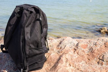 Turist veya seyahat etmek sırt çantası kaya deniz kıyısında arka plan ile. Yaz tatil kavramı