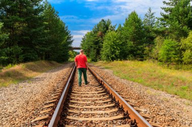 Yalnız adam tren yolunda yürüyor.