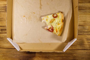 Tahta bir masadaki karton kutuda bir dilim pizza. Üst Manzara. Yemek teslimatı, fast food, pizza teslimatı.