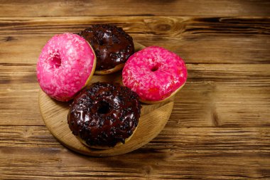 Tahta bir masada lezzetli pembe ve çikolatalı çörekler.