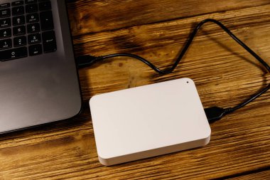 Harici HDD, tahta bir masadaki dizüstü bilgisayara bağlı. Veri depolama kavramı