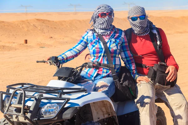 Young couple in safari trip through egyptian desert driving ATV. Quad bikes safari in the desert near Hurghada, Egypt