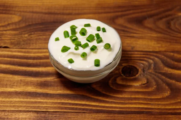 Crema Agria Con Cebolla Verde Cuenco Vidrio Sobre Mesa Madera —  Fotos de Stock