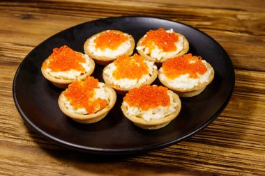 Kırmızı havyarlı turta ve ahşap bir masada yumuşak peynir.