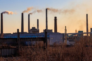 Dumanlı boruları olan eski bir fabrika manzarası. Hava kirliliği, çevresel hasar