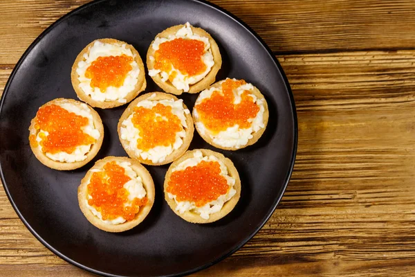 Kırmızı havyarlı turta ve ahşap bir masada yumuşak peynir. Üst görünüm