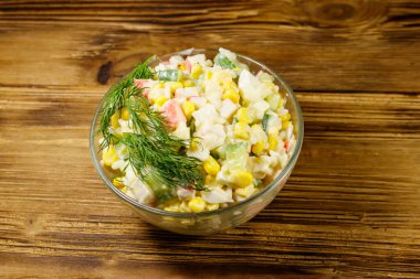 Yengeç çubuklu salata, mısır, salatalık, yumurta, pirinç ve mayonez ahşap masada.