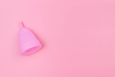 Pembe arka planda tekrar kullanılabilir silikon adet kupası. Üst görünüm, boşluğu kopyala. Kadın hijyeni, jinekoloji ve sağlık kavramı