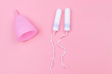 Pembe silikon regl kupası ve pembe arka planda tampon. Üst Manzara. Kadın hijyeni, jinekoloji ve sağlık kavramı