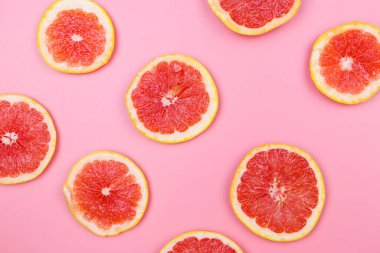 Pembe arka planda greyfurt dilimleri