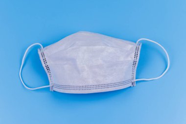 Mavi arka planda tek kullanımlık koruyucu tıbbi maske. Üst görünüm