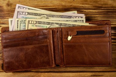 Ahşap masanın üzerinde Amerikan doları olan açık cüzdan. Üstte görüntü