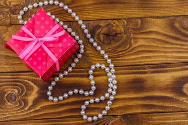 Ahşap arka planda hediye kutusu ve inci kolye.