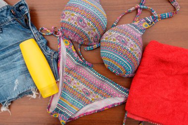 Ahşap arka plan üzerinde beachwear kümesi. Güneş kremi, havlu, mayo ve jean şort. Yaz tatil kavramı
