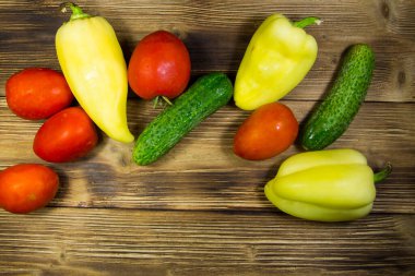 Domates, salatalık ve biber kopya alanı ile ahşap arka plan üzerinde. Üstten Görünüm