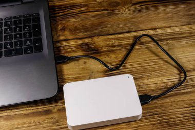 Harici HDD, tahta bir masadaki dizüstü bilgisayara bağlı. Veri depolama kavramı