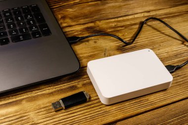 Harici HDD, tahta bir masadaki dizüstü bilgisayara ve USB flash diske bağlı. Veri depolama kavramı