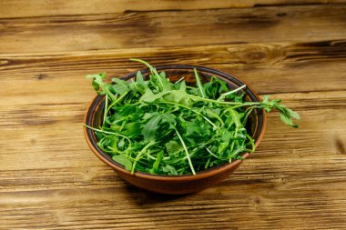 Tahta bir masada seramik kasede taze yeşil roka. Sağlıklı gıda veya vejetaryen konsepti