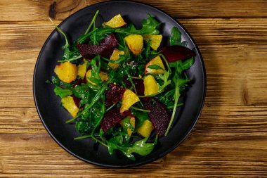 Lezzetli roka salatası, pancar kökü ve portakallar ahşap masada. Üst Manzara. Sağlıklı gıda veya vejetaryen konsepti